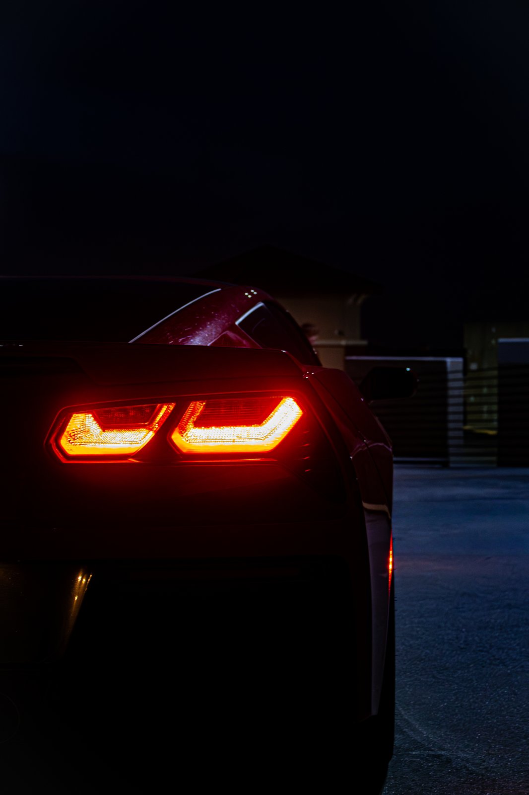 Black Mazda MX-5 and red Corvette Stingray together in a parking garage at night