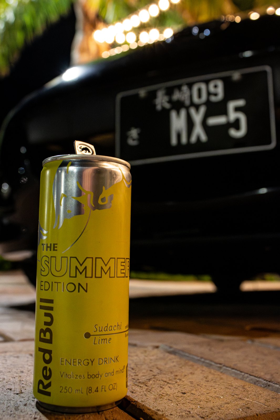 Red Bull Summer Edition can with Mazda MX-5 license plate background — automotive lifestyle photography
