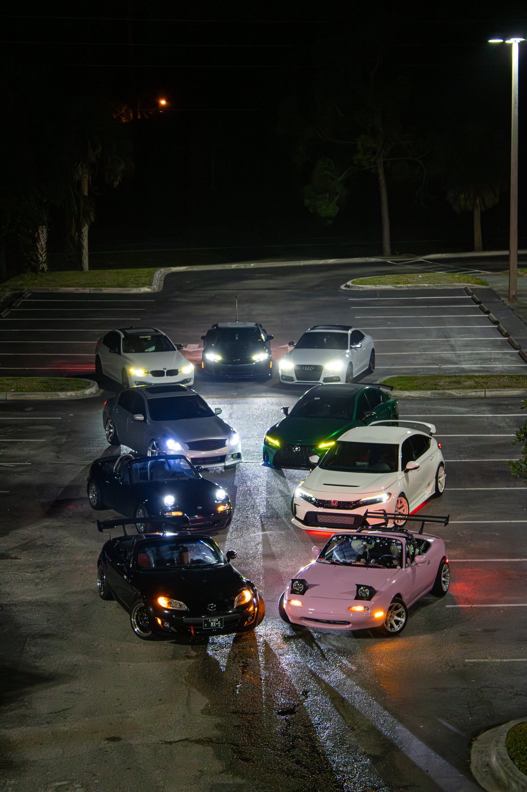 Aerial view of a Southwest Florida car meet with imports and muscle cars in a circle formation at night