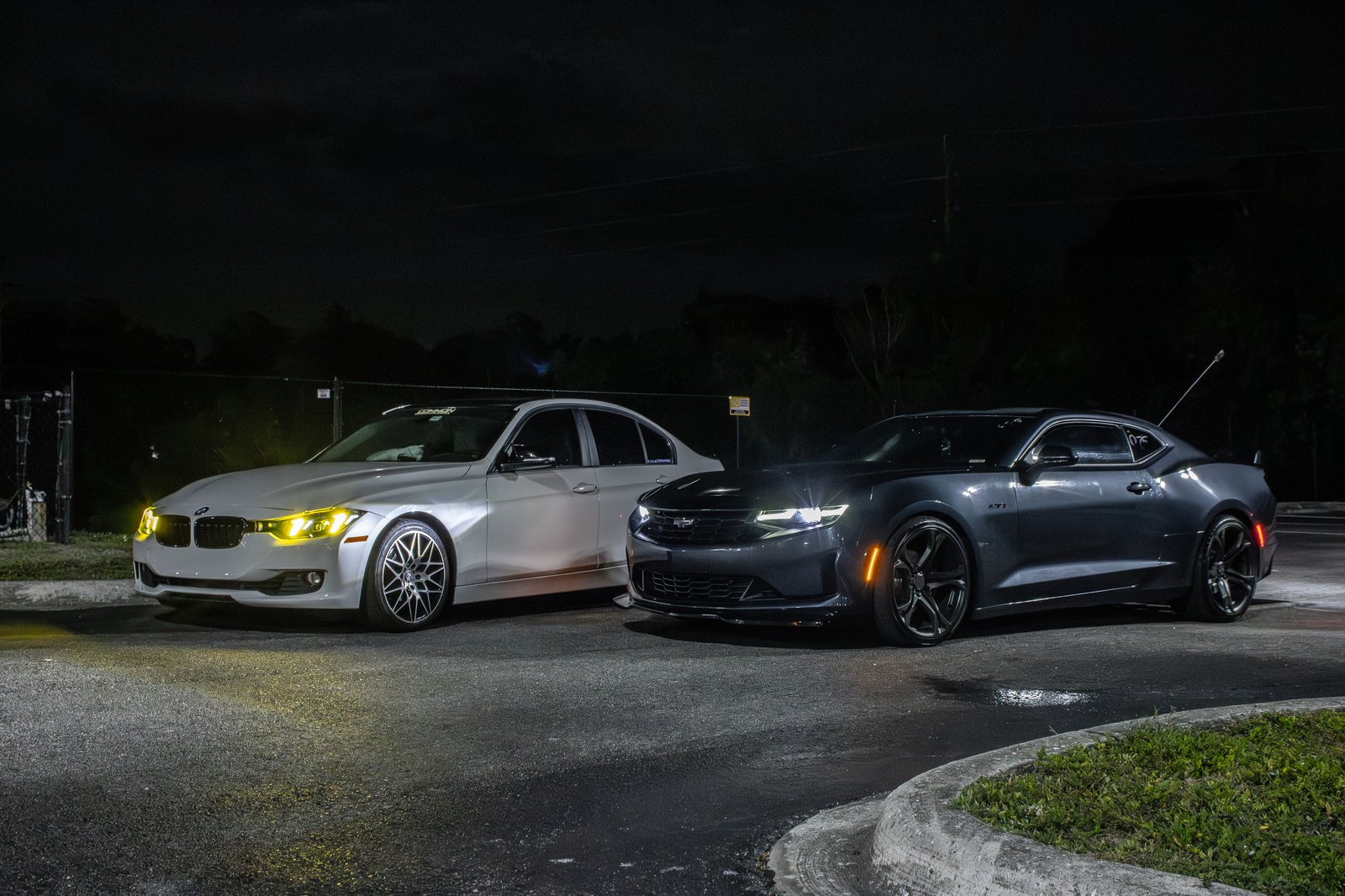 White BMW and Camaro RS facing off at night — automotive lifestyle photography in Southwest Florida