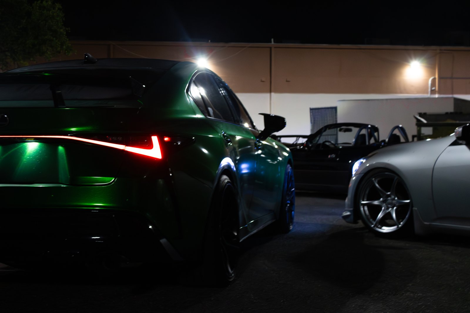 Green wrapped Lexus IS rear quarter with red taillight illuminated at night